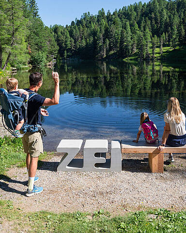 Familie erlebt den ZEITPlatz Die Ringe der ZEIT am Grünsee auf der Turracher Höhe mit Steinwurf ins Wasser