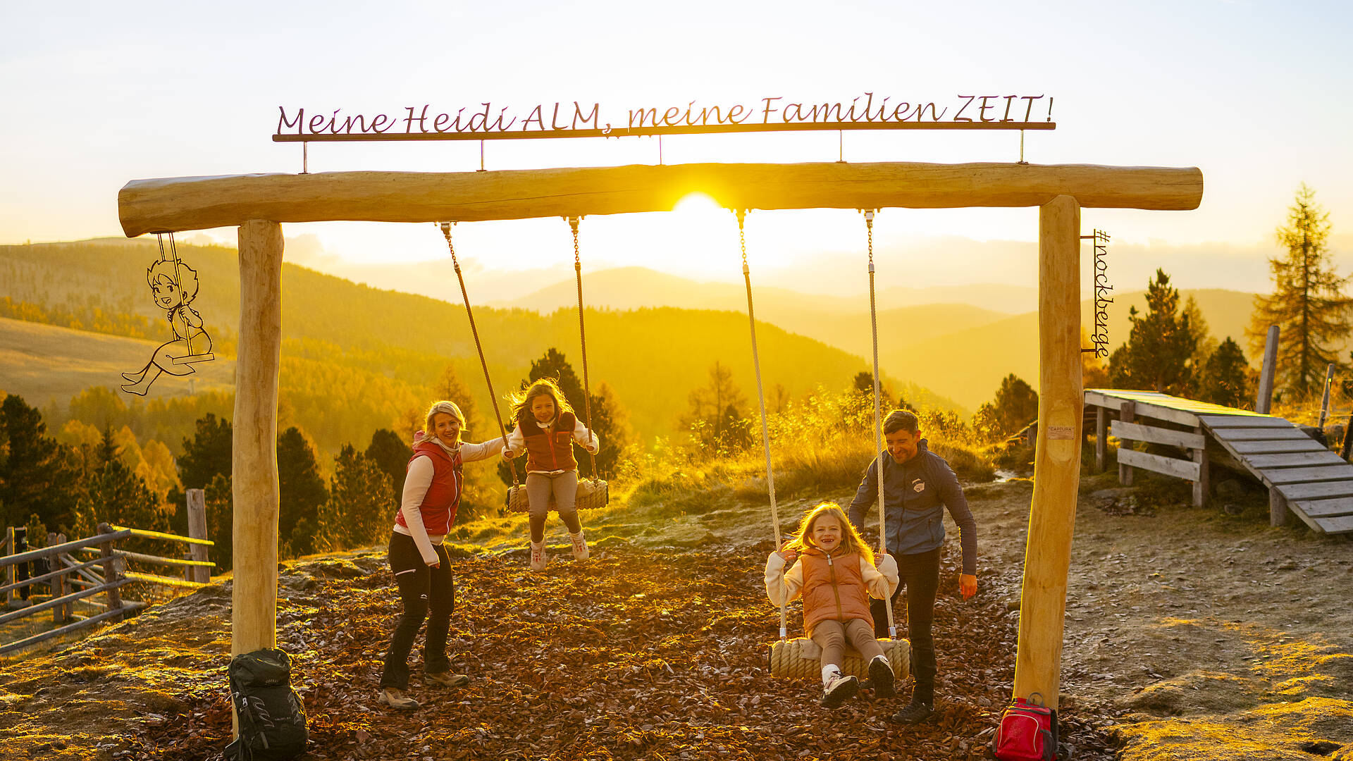Familie am ZEITplatz mit Panoramaschaukel bei Sonnenuntergang in den Nockbergen.
