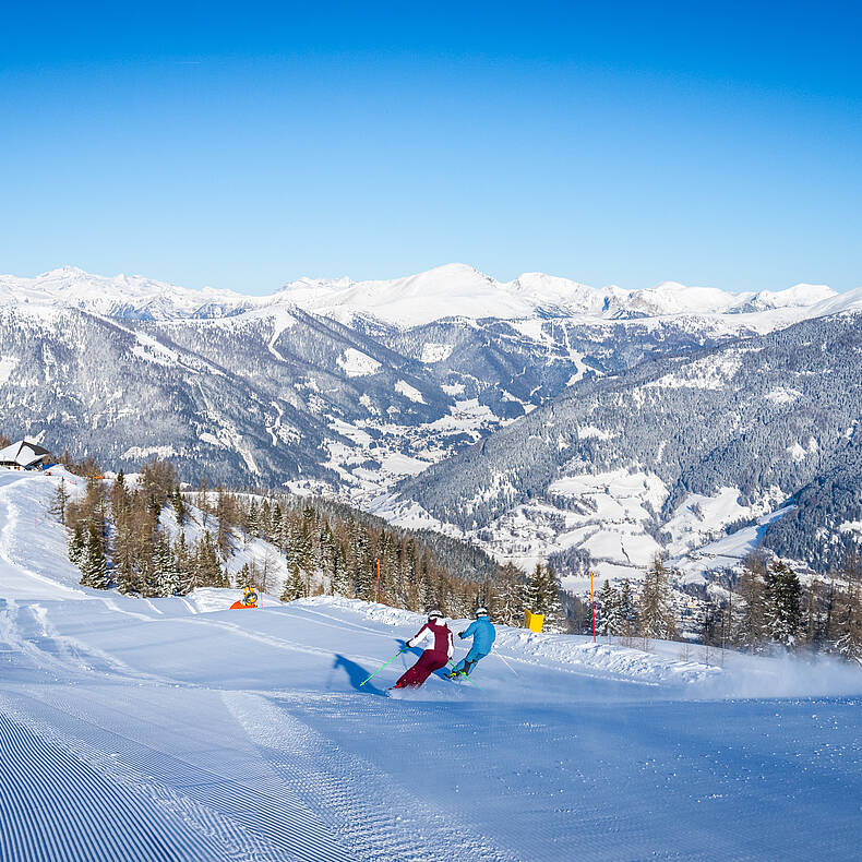 Zwei Skifahrer mit Ausblick auf die Nockberge im Skigebiet Bad Kleinkirchheim