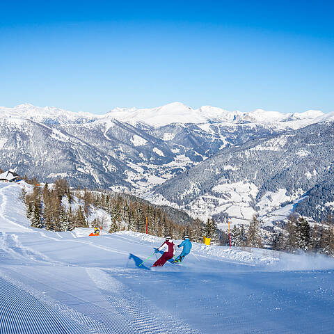 Zwei Skifahrer mit Ausblick auf die Nockberge im Skigebiet Bad Kleinkirchheim