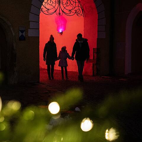 Familie geht durch beleuchteten Torbogen am Lichtweg in Millstatt