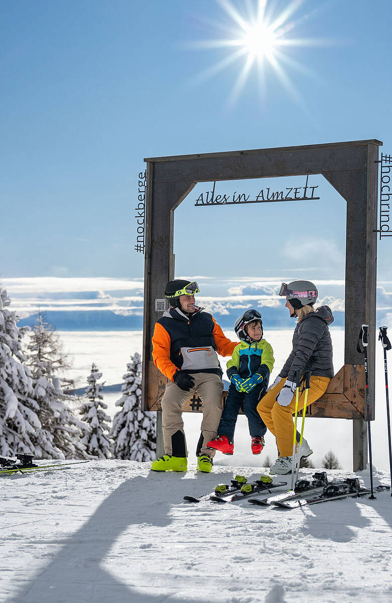 Familie mit Skiausrüstung am ZEITplatz Alles in AlmZEIT auf der Hochrindl