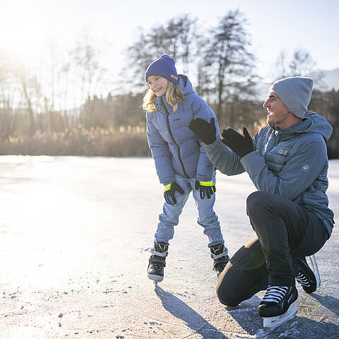 Erwachsener und Kind am zugefrorenen Flatschacher See