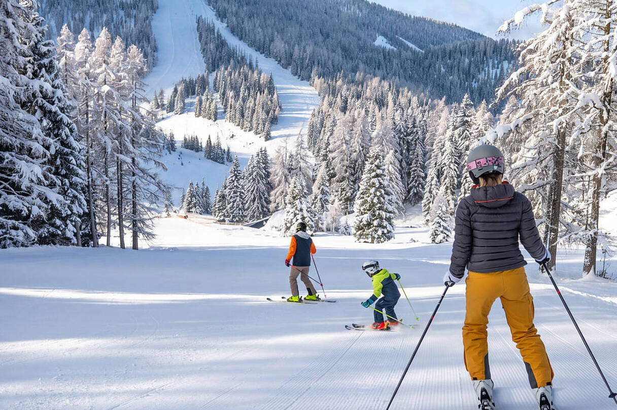 Familie beim Skifahren auf den sonnigen Pisten der Hochrindl in den Nockbergen.