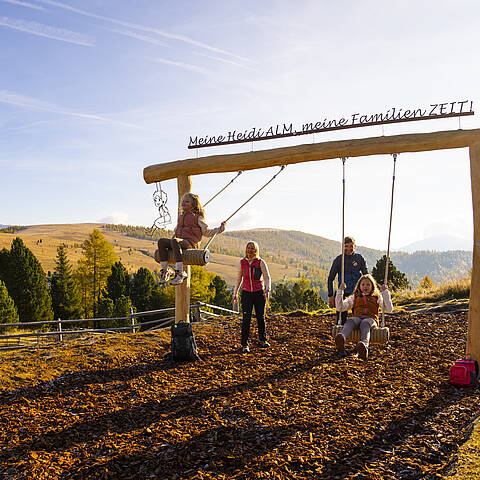 Familie bei Panoramaschaukel am ZEITplatz in den Nockbergen mit Blick über Berglandschaft.