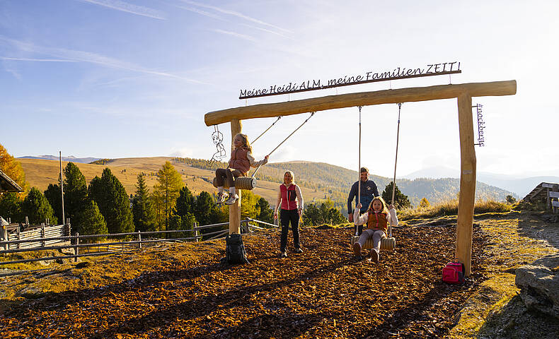 Familie bei Panoramaschaukel am ZEITplatz in den Nockbergen mit Blick über Berglandschaft.