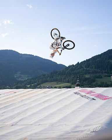 Mountainbiker bei einem Backflip-Sprung in den Bagjump Airbag in der Bike Area Obermillstatt vor Bergpanorama