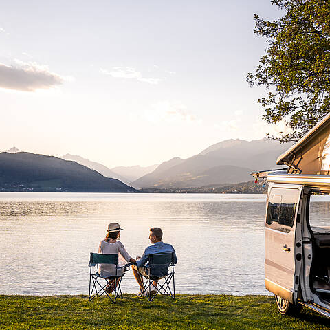 Pärchen sitzt neben Campingbus in Stühlen am See