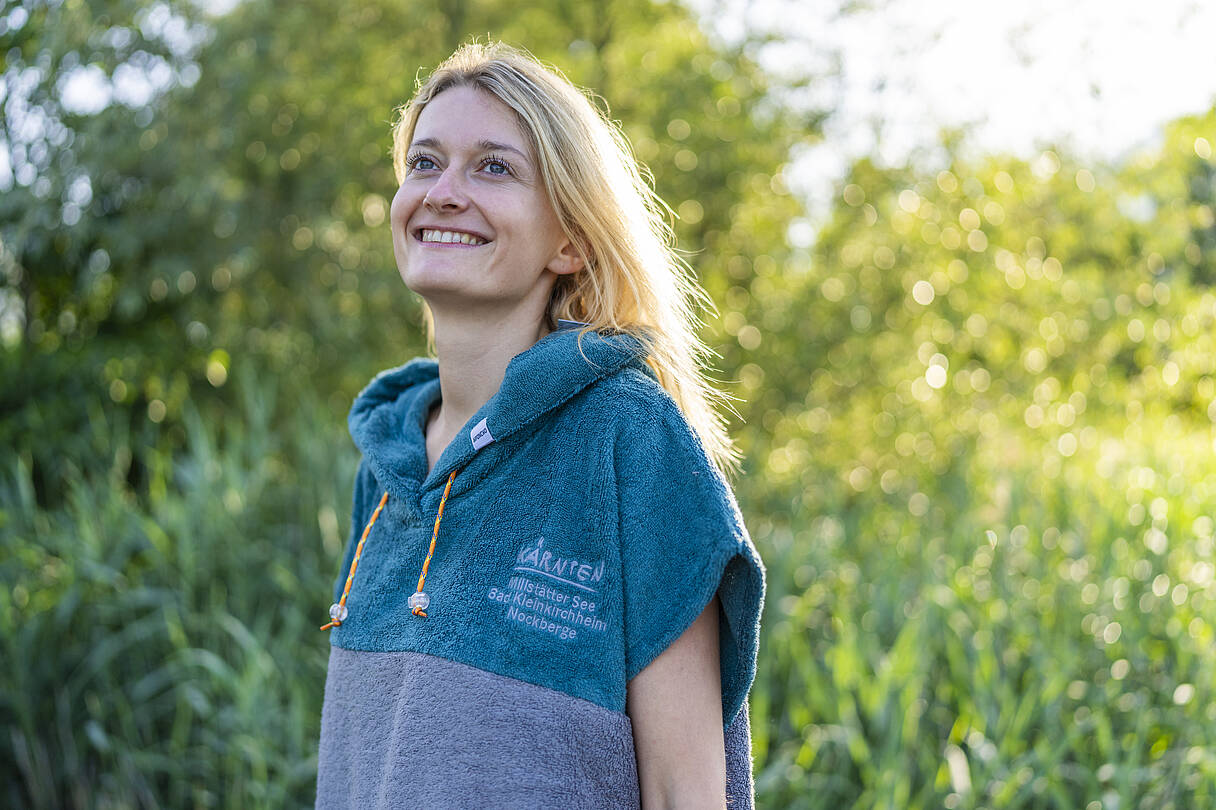 Junge Frau trägt Badeponcho in blau grau mit Logo auf der Brust