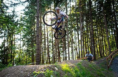 Ein Junge hüpft mit seinem Mountainbike über die Jumpline im Bikepark
