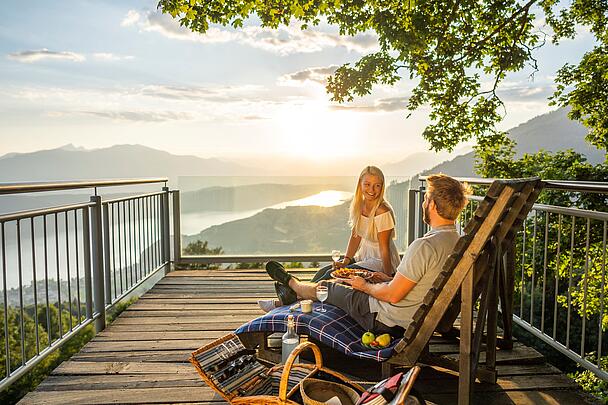 Pärchen genießt auf Bank mit einem Picknick am Sternenbalkon die Sonne