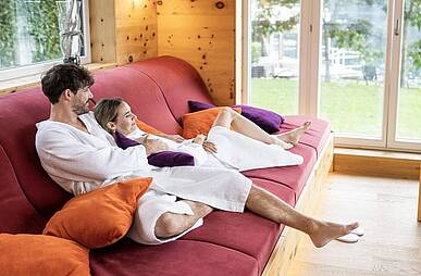 Pärchen liegt auf einer gemütlichen Liege und blickt vom Ruheraum des Badehaus Millstätter See nach draußen