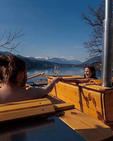 Pärchen entspannt in einer Outdoor-Badewanne direkt am Millstätter See mit Bergblick