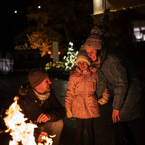 Familie steht an einer Feuerschale am Lichtweg in Millstatt