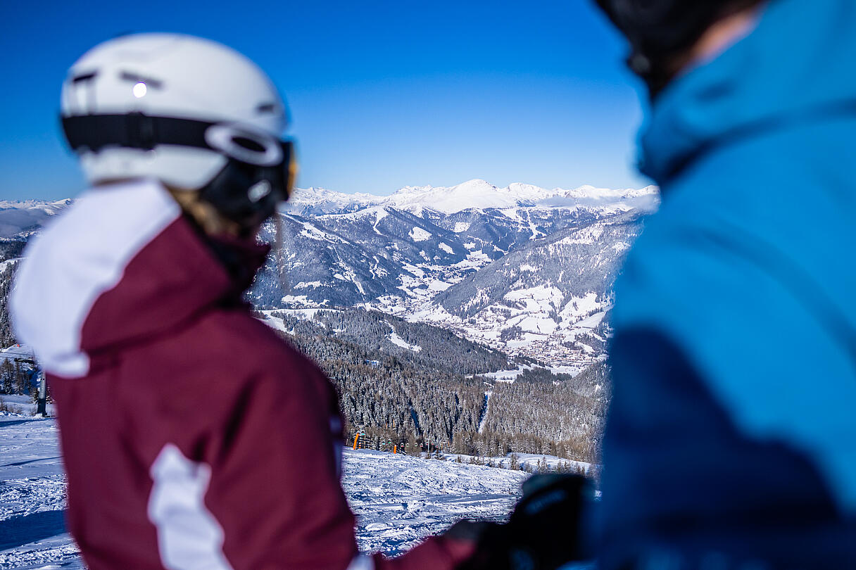 Zwei Skifahrer mit Blick über das verschneite Tal und die Nockberge im Skigebiet Bad Kleinkirchheim
