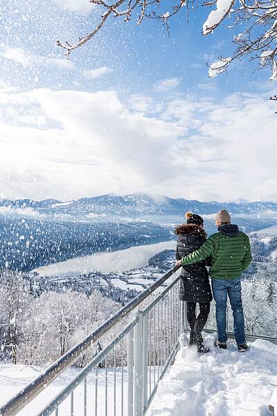 Pärchen steht im Winter am Sternenbalkon und schaut auf den Millstätter See