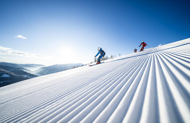 Skifahrer fahren die frisch präparierte Piste in Bad Kleinkirchheim hinunter