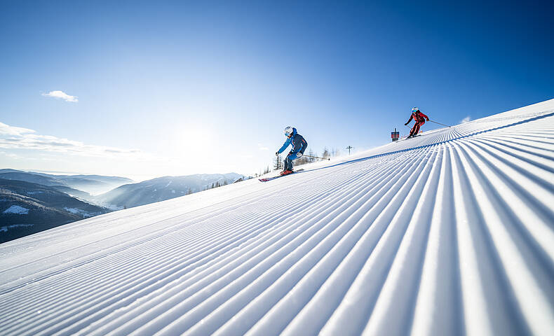Skifahrer fahren die frisch präparierte Piste in Bad Kleinkirchheim hinunter