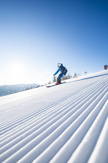Skifahrer fahren die frisch präparierte Piste in Bad Kleinkirchheim hinunter