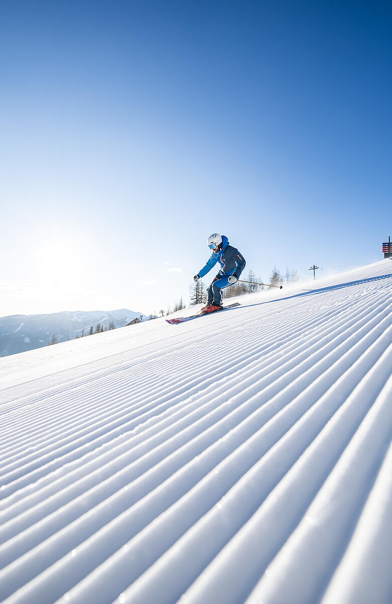 Skifahrer fahren die frisch präparierte Piste in Bad Kleinkirchheim hinunter