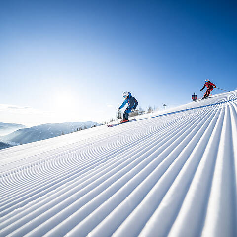 Skifahrer fahren die frisch präparierte Piste in Bad Kleinkirchheim hinunter