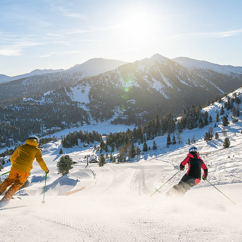 Skifahrer genießen das Herunterfahren der Piste bei Sonnenschein auf der Turracher Höhe
