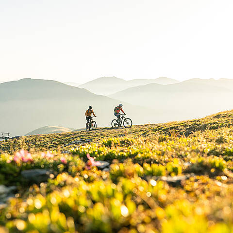 2 Personen radeln in den Nockbergen einen Gipfel hinauf