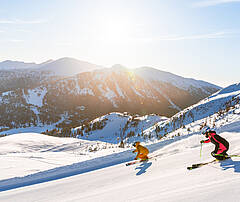 Skifahrer fahren die Piste auf der Turracher Höhe hinunter