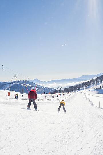 Familie fährt im Skigebiet Bad Kleinkirchheim eine breite Piste hinunter