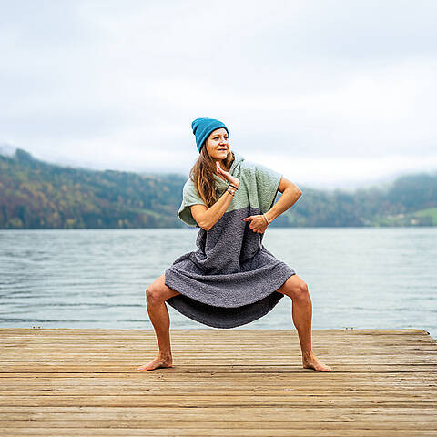 Frau wärmt sich mit Badeponcho richtig für das Kaltbaden auf