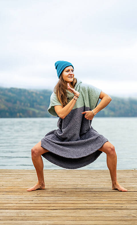 Frau wärmt sich mit Badeponcho richtig für das Kaltbaden auf