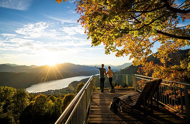 Pärchen steht am Sternenbalkon im Herbst mit Blick auf den Millstätter See