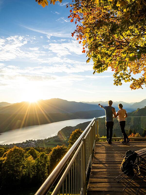 Pärchen steht am Sternenbalkon im Herbst mit Blick auf den Millstätter See