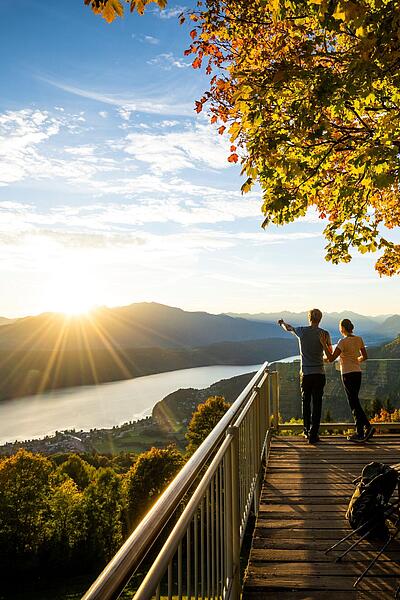 Pärchen steht am Sternenbalkon im Herbst mit Blick auf den Millstätter See